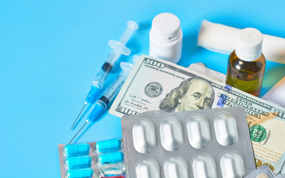 Medication and syringes laid out with a 100 dollar bill on a blue background